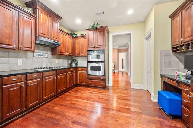 kitchen featuring visible vents, wood finished floors, under cabinet range hood, and stainless steel appliances
