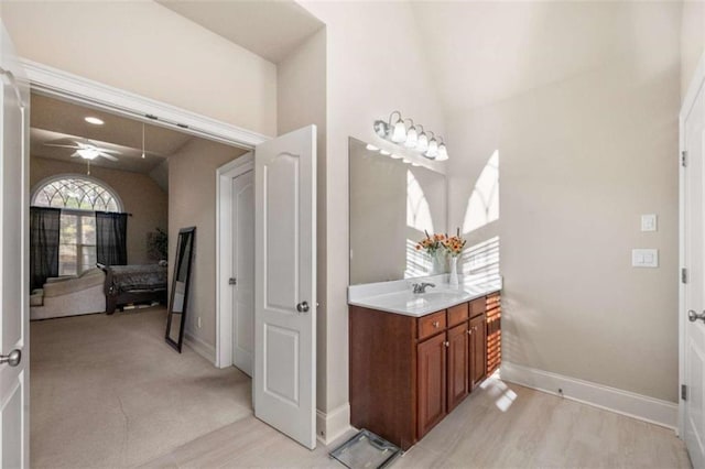 bathroom featuring a ceiling fan, vanity, baseboards, and lofted ceiling