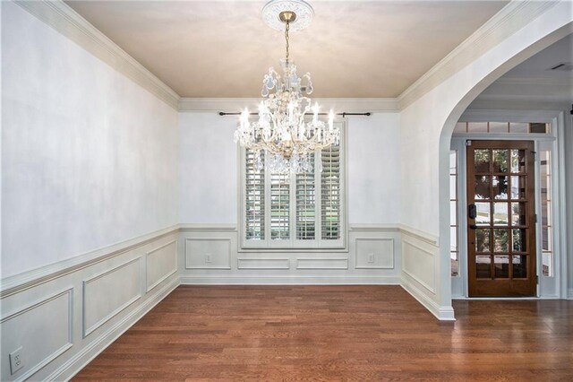 unfurnished dining area featuring ornamental molding, a notable chandelier, and dark hardwood / wood-style floors