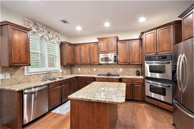 kitchen featuring appliances with stainless steel finishes, light hardwood / wood-style flooring, sink, and a kitchen island