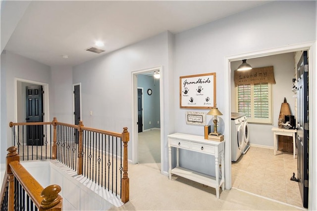 hallway featuring separate washer and dryer and light colored carpet