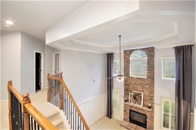 hallway featuring light carpet, ornamental molding, and a raised ceiling