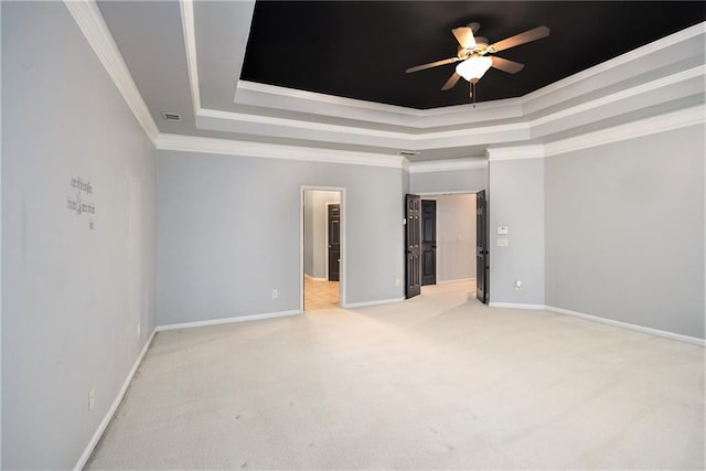 carpeted empty room with ornamental molding, a raised ceiling, and ceiling fan