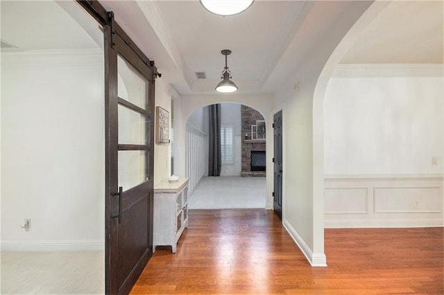 corridor with ornamental molding and hardwood / wood-style floors