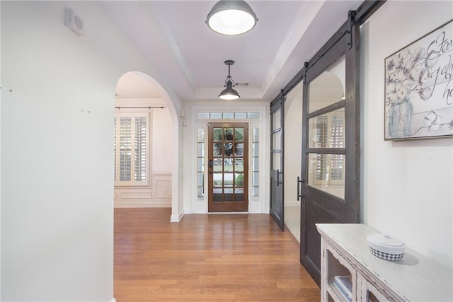 foyer featuring ornamental molding, a barn door, and wood-type flooring