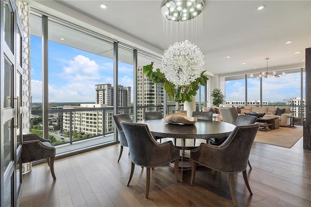 dining area featuring a chandelier, a wealth of natural light, wood-type flooring, and a city view