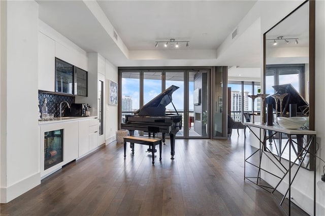 sitting room with wine cooler, dark wood-style flooring, a raised ceiling, visible vents, and wet bar