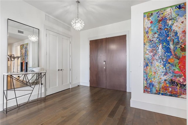 entrance foyer featuring baseboards, wood-type flooring, visible vents, and a notable chandelier