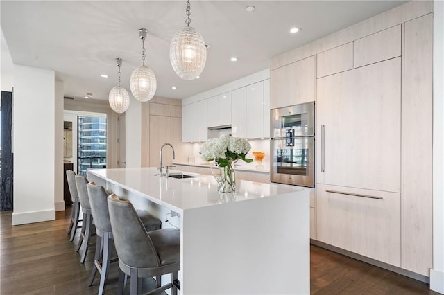 kitchen featuring dark wood finished floors, a kitchen island with sink, a sink, light countertops, and modern cabinets