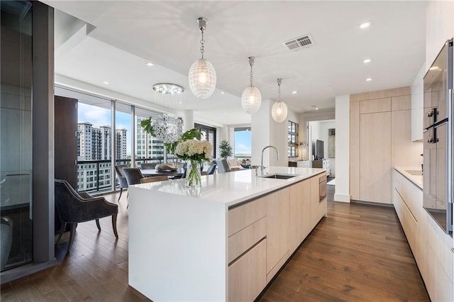 kitchen featuring modern cabinets, light brown cabinets, a sink, dark wood-style floors, and light countertops