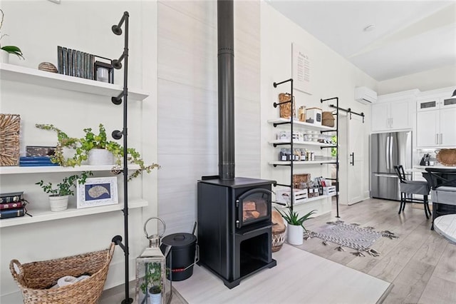 4791 Talona Rd, Talking Rock, GA 30175 - living room with a wall mounted AC, light wood-style flooring, a wood stove, baseboards, and a barn door