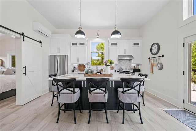4791 Talona Rd, Talking Rock, GA 30175 - kitchen with under cabinet range hood, a wall unit AC, freestanding refrigerator, a barn door, and backsplash