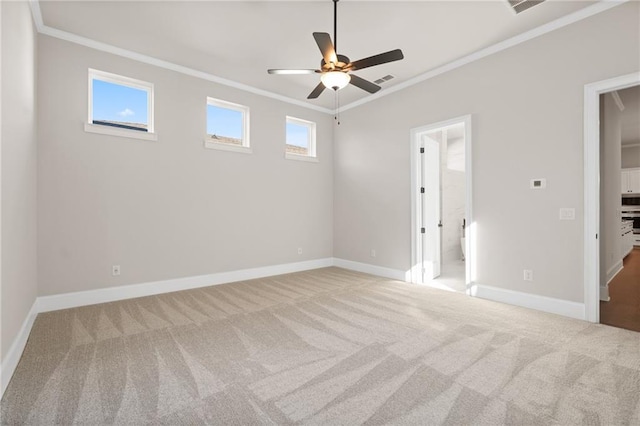 spare room featuring crown molding, a wealth of natural light, light colored carpet, and ceiling fan