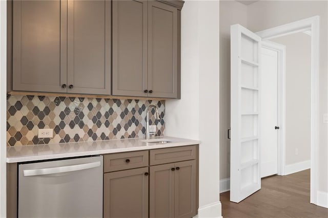 kitchen featuring tasteful backsplash, wood-type flooring, sink, gray cabinetry, and stainless steel dishwasher