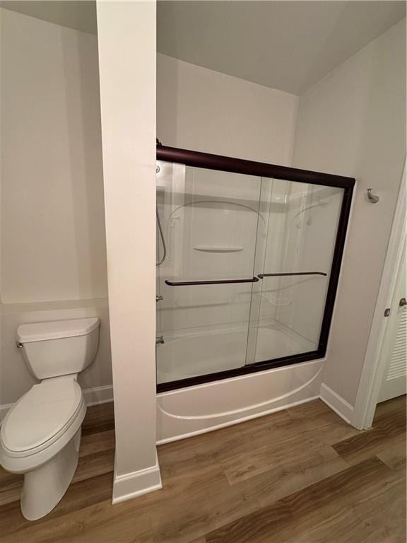 full bathroom featuring combined bath / shower with glass door, wood finished floors, toilet, and baseboards