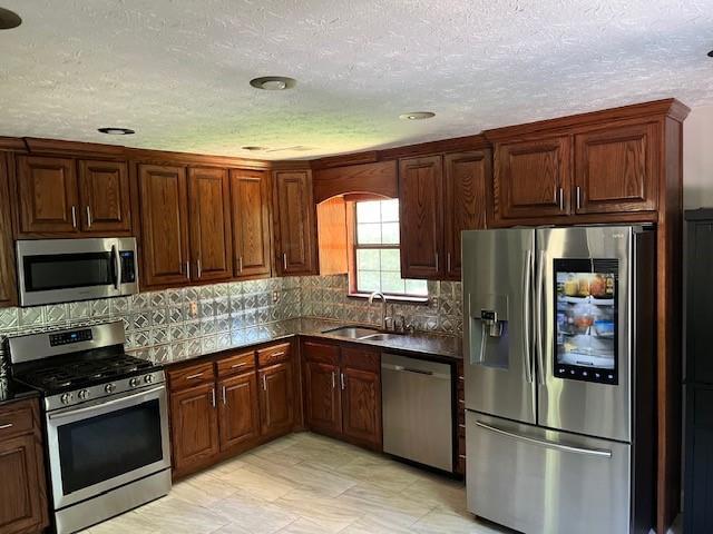 kitchen featuring stainless steel appliances, sink, and a textured ceiling