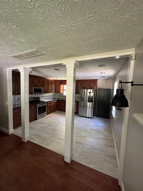 kitchen featuring tasteful backsplash, stainless steel appliances, and decorative columns