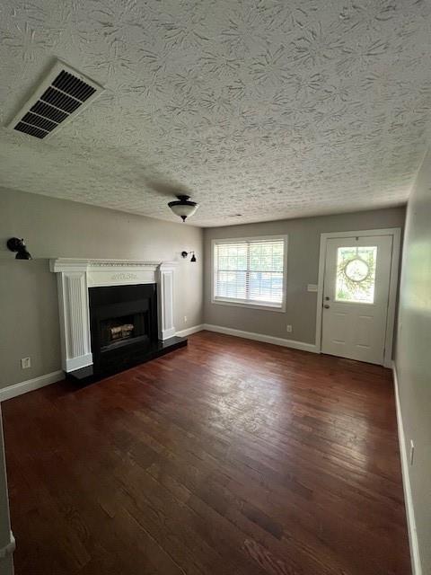 unfurnished living room with dark hardwood / wood-style flooring and a textured ceiling