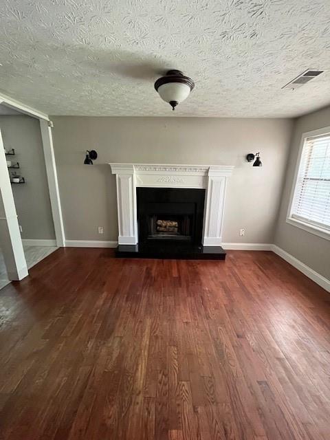 unfurnished living room with a textured ceiling and dark hardwood / wood-style flooring