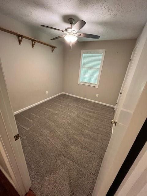 unfurnished room with ceiling fan, a textured ceiling, and dark colored carpet