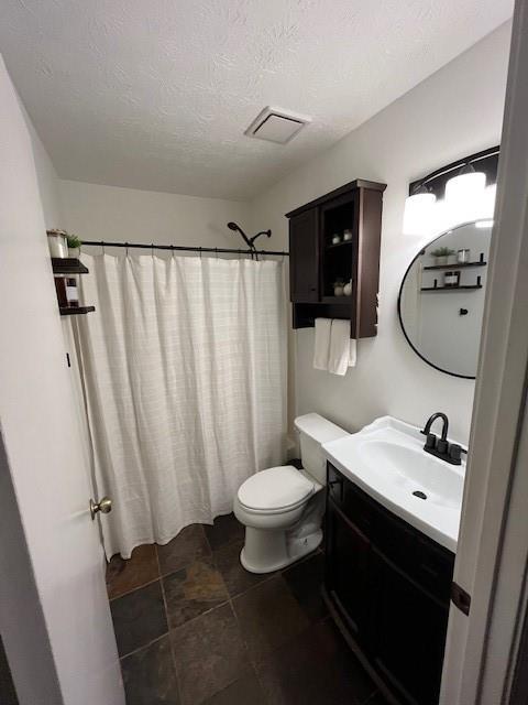 bathroom with vanity, toilet, curtained shower, and a textured ceiling