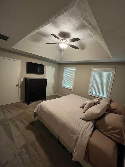 bedroom with ceiling fan, a tray ceiling, and carpet floors