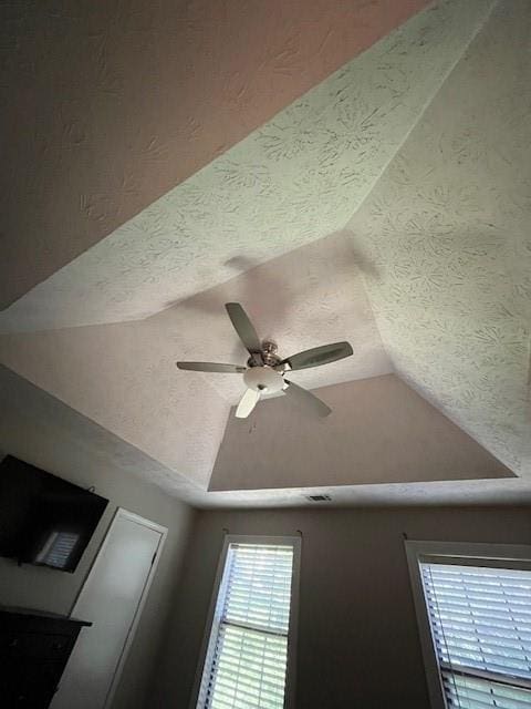 interior details featuring ceiling fan, a textured ceiling, and a tray ceiling