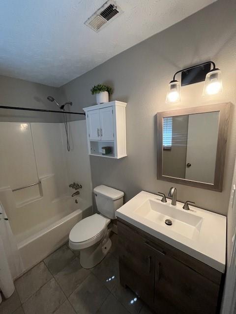 full bathroom with washtub / shower combination, vanity, toilet, tile patterned floors, and a textured ceiling