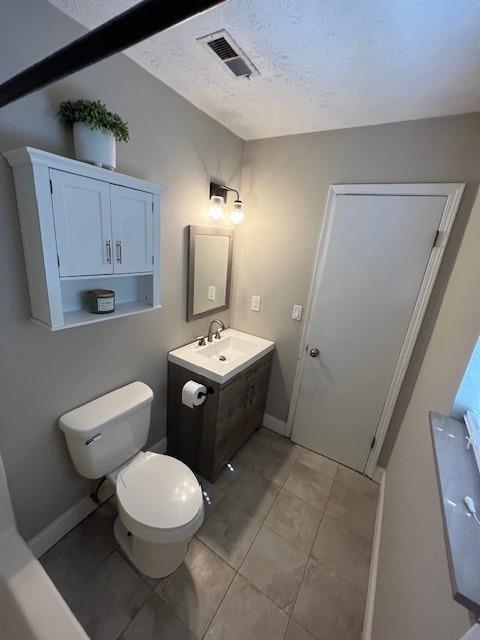 bathroom with vanity, a textured ceiling, and toilet