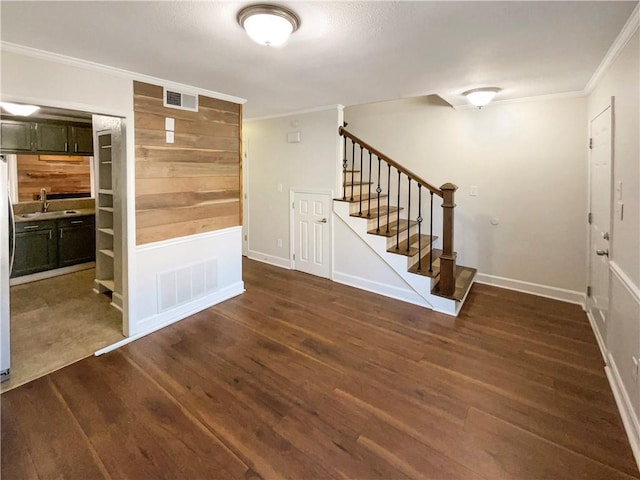 foyer entrance with ornamental molding, dark hardwood / wood-style floors, sink, and wooden walls