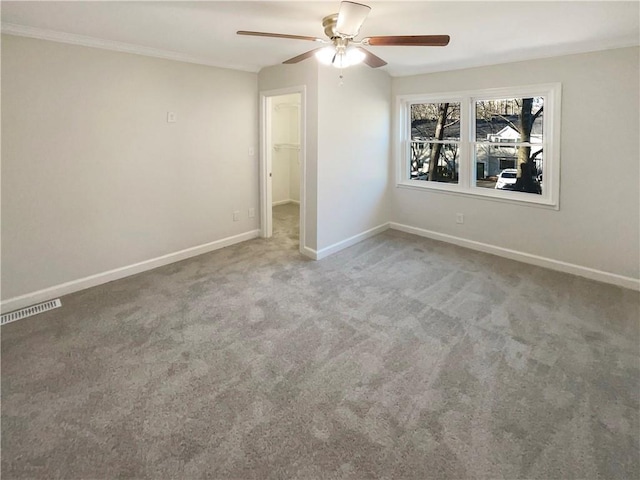 empty room with crown molding, ceiling fan, and carpet