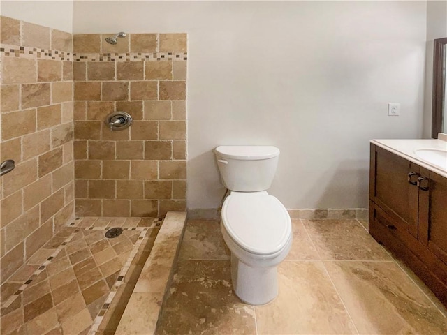 bathroom featuring tiled shower, vanity, and toilet