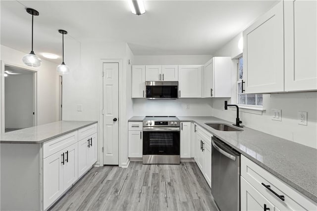 kitchen featuring sink, appliances with stainless steel finishes, hanging light fixtures, light stone countertops, and white cabinets