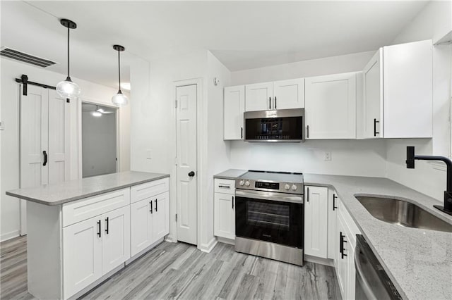 kitchen featuring appliances with stainless steel finishes, pendant lighting, sink, white cabinets, and kitchen peninsula