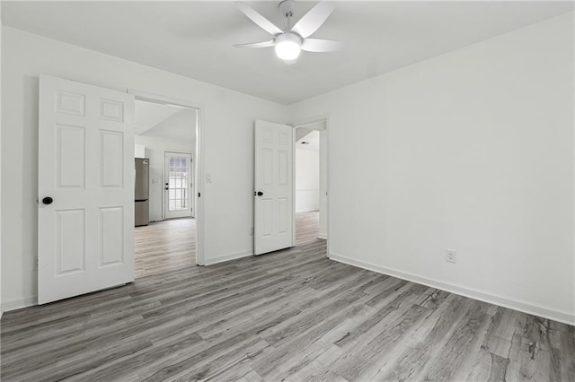 unfurnished bedroom with stainless steel fridge, ceiling fan, and light wood-type flooring