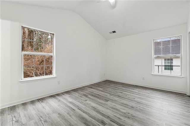 unfurnished room featuring lofted ceiling, ceiling fan, light hardwood / wood-style flooring, and a healthy amount of sunlight