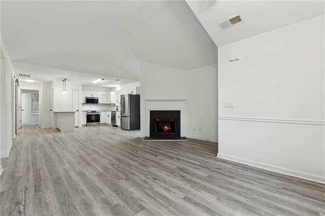 unfurnished living room featuring vaulted ceiling and light wood-type flooring