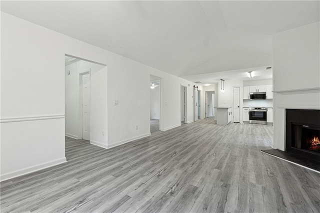 unfurnished living room featuring light hardwood / wood-style floors and vaulted ceiling