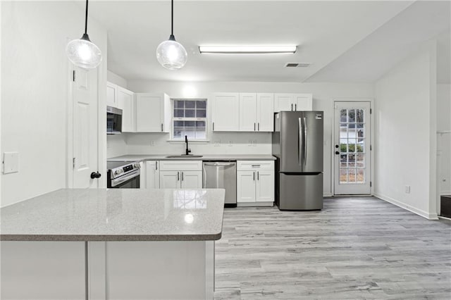 kitchen with stainless steel appliances, sink, hanging light fixtures, and white cabinets