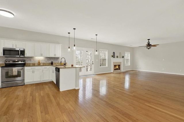 kitchen featuring sink, white cabinetry, tasteful backsplash, decorative light fixtures, and stainless steel appliances