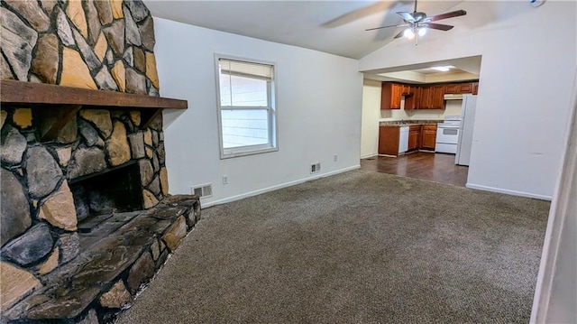 unfurnished living room with dark colored carpet, ceiling fan, a fireplace, and vaulted ceiling