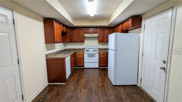 kitchen with white appliances, a raised ceiling, dark wood-type flooring, and sink