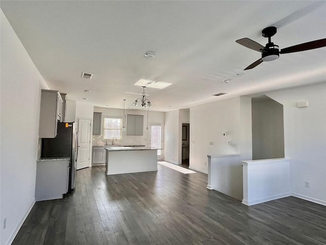 kitchen with gray cabinetry, hanging light fixtures, dark hardwood / wood-style floors, a kitchen island, and backsplash