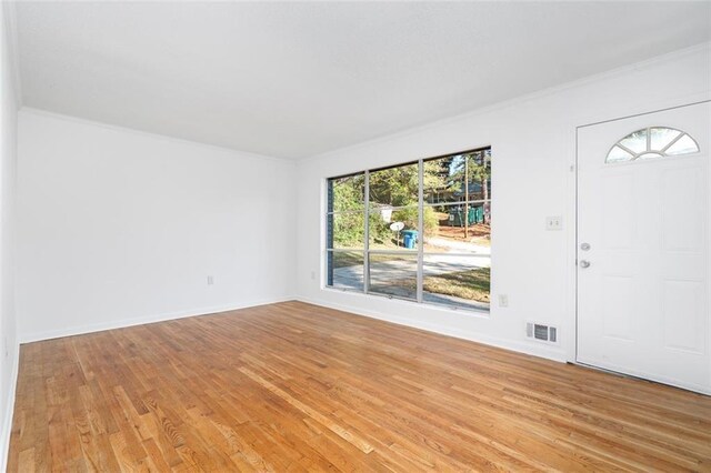 interior space with visible vents, crown molding, light wood-style flooring, and baseboards