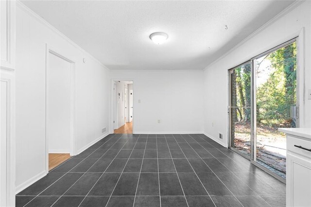 unfurnished room with dark tile patterned floors, ornamental molding, and baseboards