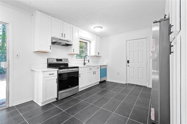 kitchen featuring dark tile patterned floors, stainless steel appliances, white cabinetry, a sink, and under cabinet range hood