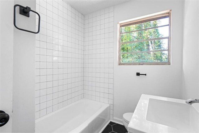 full bath with tile patterned flooring, toilet, shower / bath combination, a sink, and baseboards