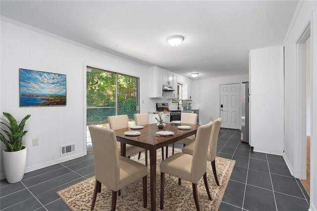 dining area featuring ornamental molding, dark tile patterned flooring, visible vents, and baseboards