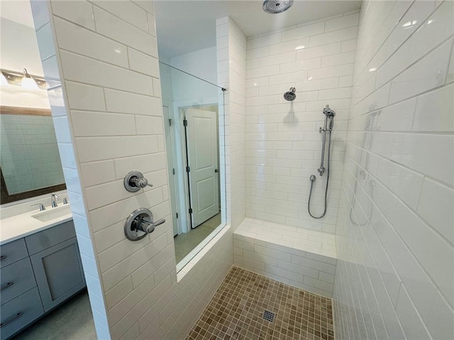 bathroom with tile patterned flooring, vanity, and a tile shower