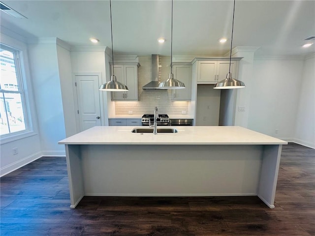 kitchen featuring dark hardwood / wood-style flooring, sink, wall chimney range hood, a center island with sink, and hanging light fixtures